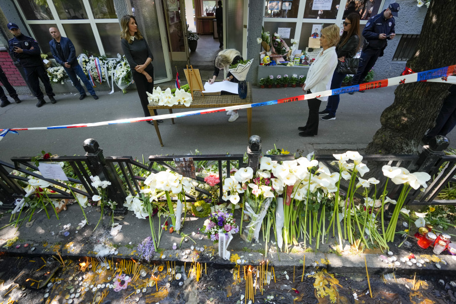 A girl signs the book of condolences in front of the Vladimir Ribnikar school, two days after a 13-year-old boy used his father's guns to kill eight fellow students and a guard, in Belgrade, Serbia, Friday, May 5, 2023. The bloodshed sent shockwaves through a Balkan nation scarred by wars, but unused to mass murders.