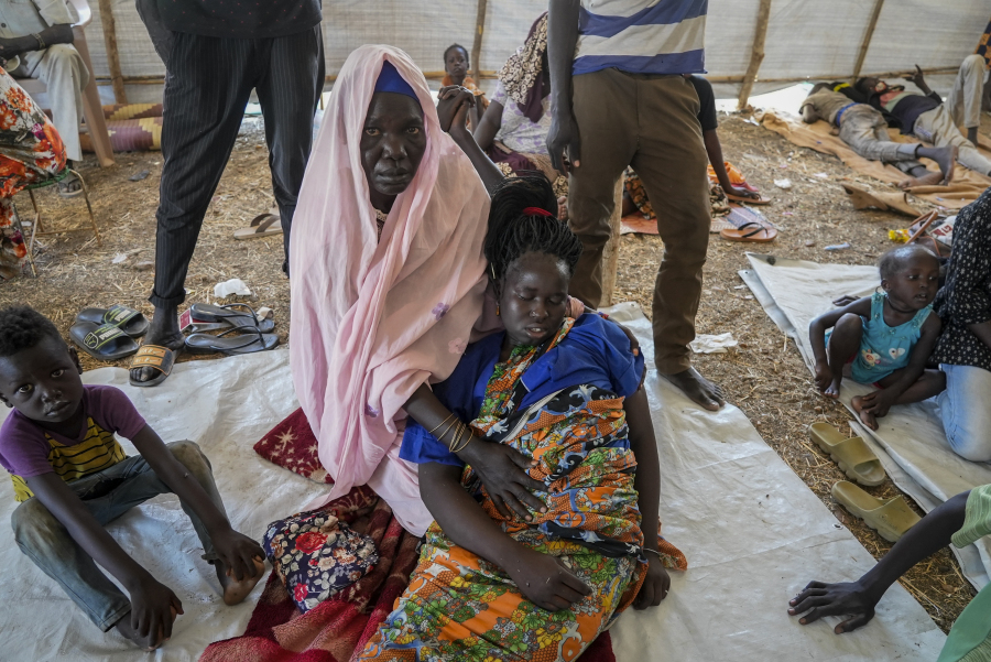 A woman who crossed from Sudan to South Sudan holds another, who is sick, at a makeshift clinic at the Joda border crossing in South Sudan Tuesday, May 16, 2023. Tens of thousands of South Sudanese are flocking home from neighboring Sudan, which erupted in violence last month.