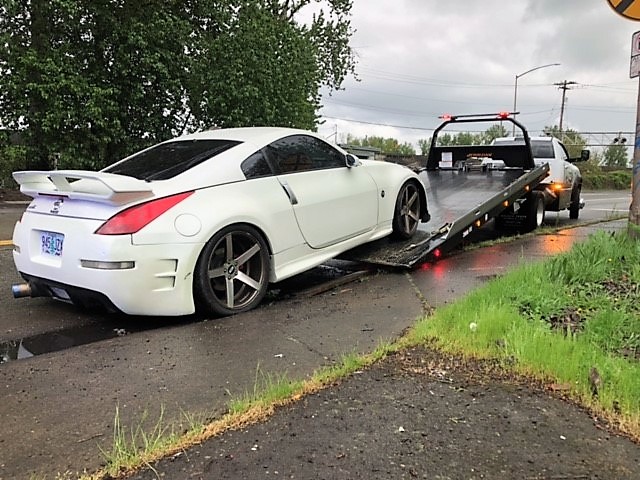 A white Nissan coupe with a spoiler is loaded onto a flatbed tow truck after a street racing mission in North Portland Friday night. The Portland Police Bureau arrested three Vancouver men during the operation.