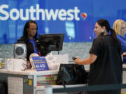 A Southwest airlines customer service representative, left, assists a traveler at the ticketing counter at Love Field airport, Friday, May 19, 2023, in Dallas.