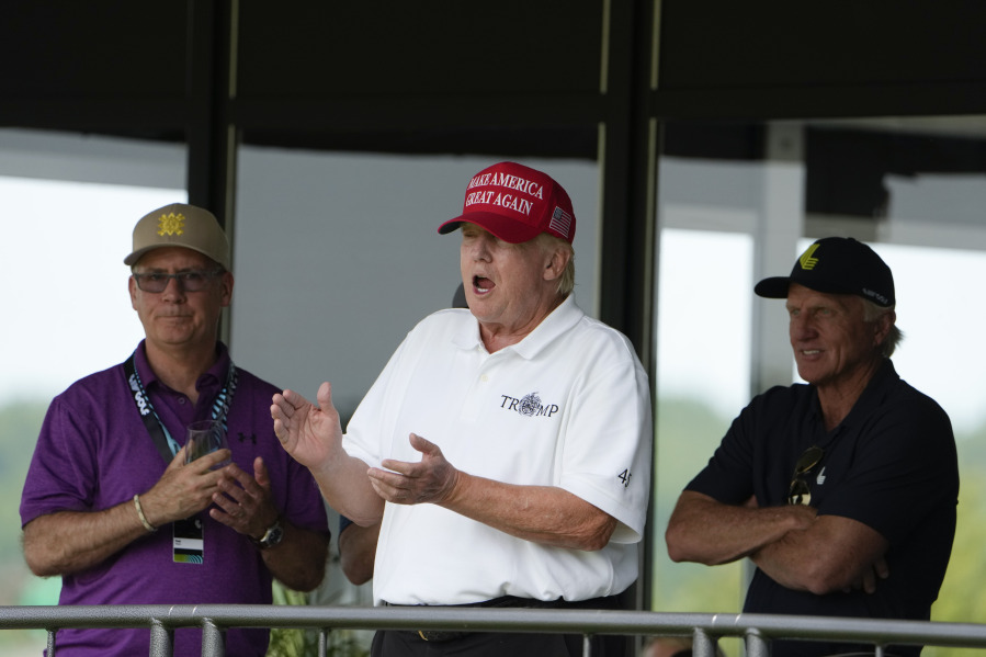 Former President Donald Trump, Greg Norman, LIV Golf CEO, right, and Paul Myler, deputy head of mission for the Australian Embassy in Washington, left, watch the second round of the LIV Golf at Trump National Golf Club, Saturday, May 27, 2023, in Sterling, Va.