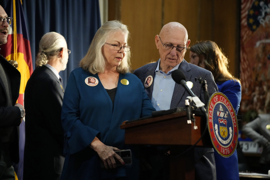 File--Sandy and Lonnie Phillips, who lost their daughter in the mass shooting at a theatre in Aurora, Colo., look on before Colorado Governor Jared Polis signs four gun control bills into law during a ceremony Friday, April 28, 2023, in the State Capitol in Denver.