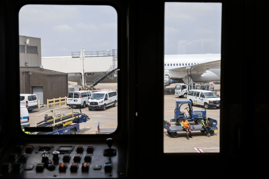 Members of the ground crew is seen through a boarding bridge as they await for an American Airlines flight on May 9, 2023, at DFW Airport.