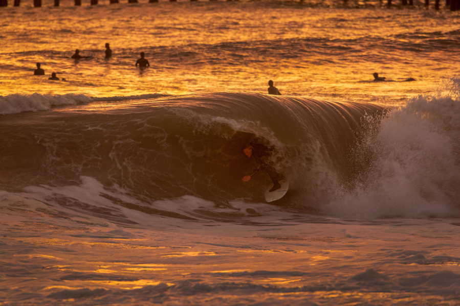With the golden glow of the sunset, surfer Dylan Sloan, 15, of Huntington Beach, gets a coveted tube ride while surfing big waves generated by winter storms at the Seal Beach pier in January. (Allen J.