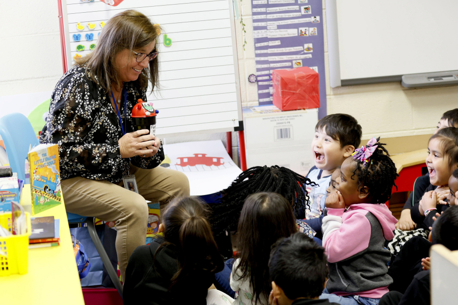 Students at a private Head Start school in Cobb County, Ga., react as Sally Miller, who works for the Marietta City Schools' public pre-K program, teaches them phonological awareness skills using a prop named Momo the monster. She visited the private school to coach its teachers.