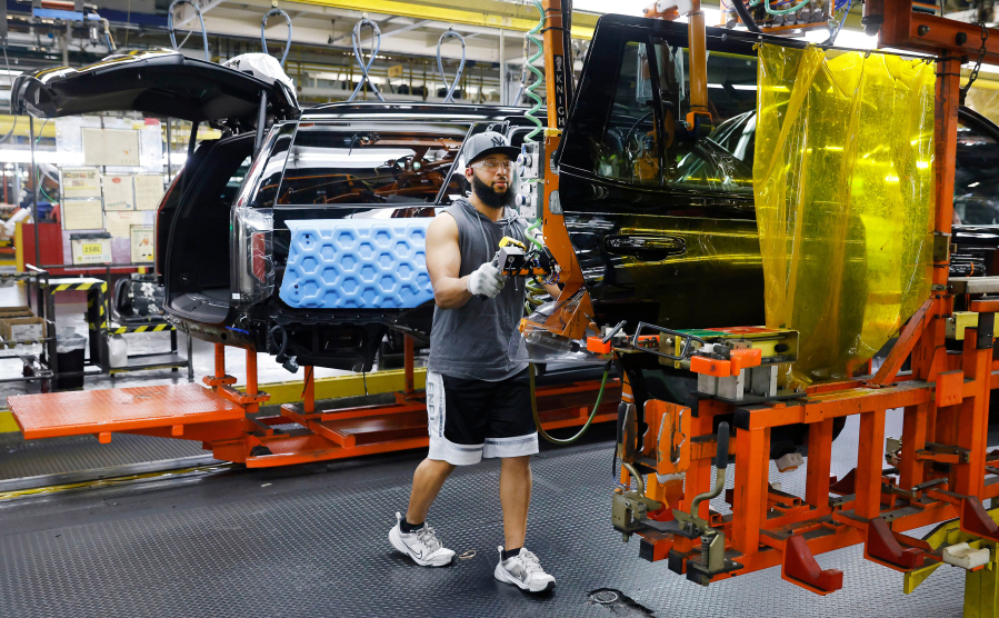 Assembly team worker Jalon Hogan uses a machine to move a rear door to a large SUV at General Motors Arlington Assembly plant in Arlington, Texas. The company recently announced a $500 million investment in the plant to prepare for next-generation combustion engine vehicles.