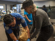 A Transportation Security Administration agent, left, checks the collar of a service dog with the dog's handler to practice going through security at Paine Field.