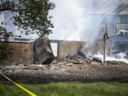 Smoke rises from the smoldering remnants of a house after a fire Thursday, June 8, 2023, on Lower River Road west of Vancouver. Two people were transported to the hospital as a result of the fire.