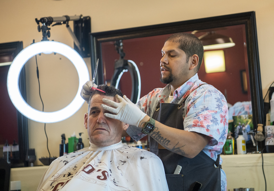 Chico's Classic Barbershop owner Raul Barasa, right, cuts the hair of Mike Tomasello, of Vancouver, on May 24. Barasa started cutting hair on a volunteer basis, then turned it into an occupation.