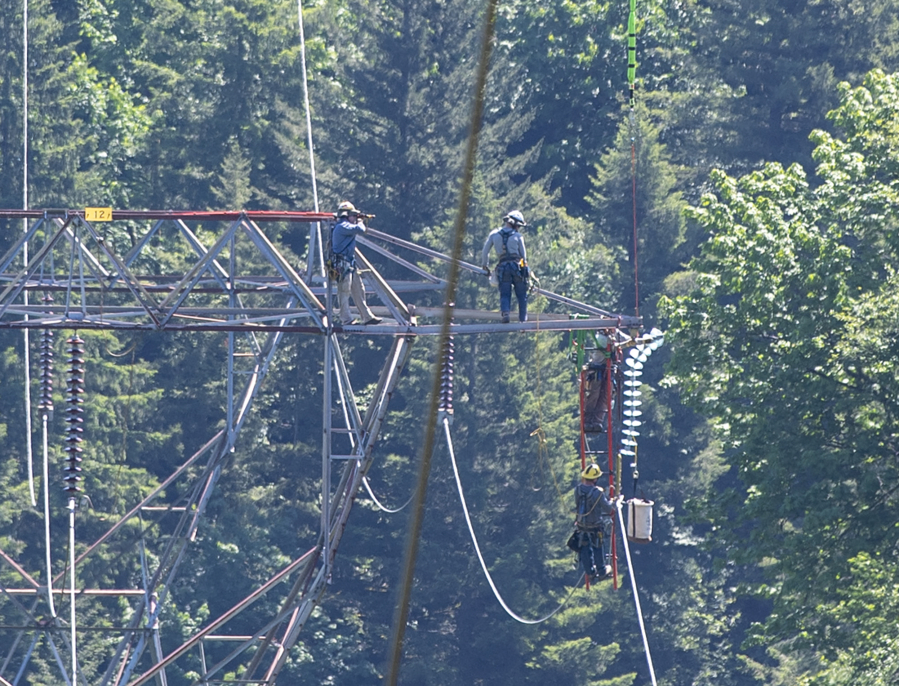 Workers install a new insulator to a Washougal transmission tower. Damaged equipment is susceptible to sparking, and faults along lines can cause a hot electrical arc.
