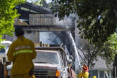 A Vancouver firefighter sprays the outside of a burned building Monday, June 5, 2023, on Northeast 68th Avenue in Vancouver. .