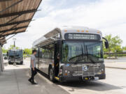Commuters step onto a new fully electric C-Tran bus on Wednesday at the 99th Street Transit Center in Vancouver. The transit agency has nine of the buses on the street, with another idled due to a software problem.