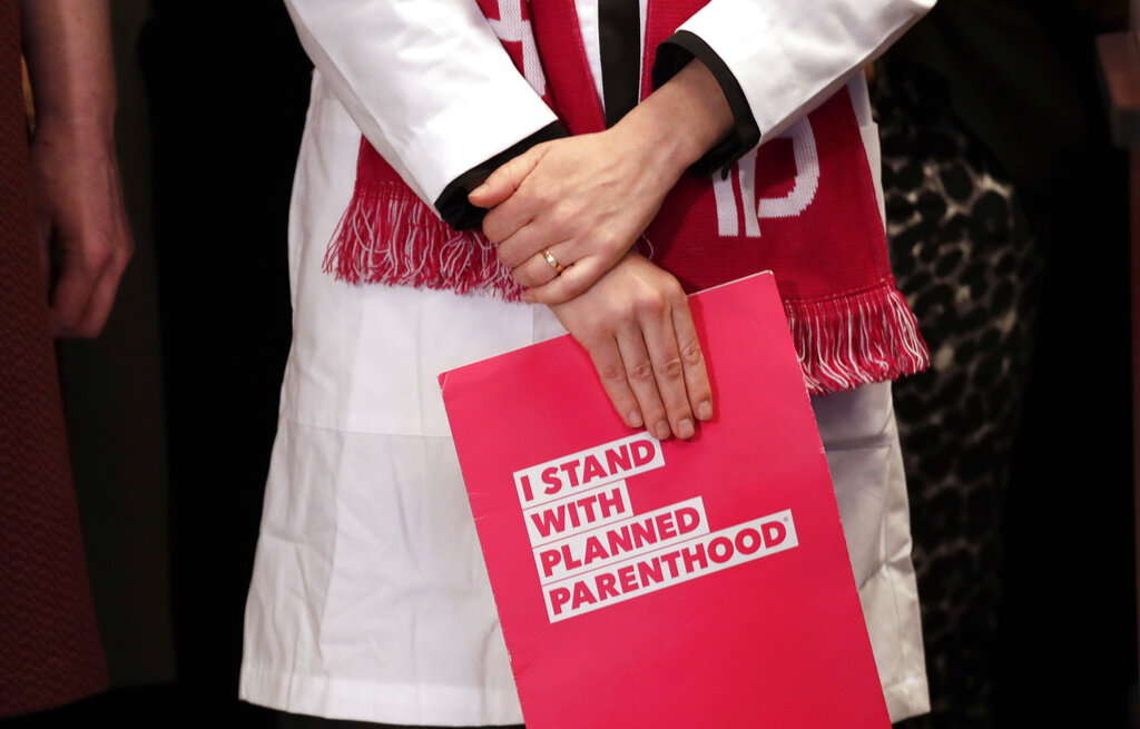 Dr. Erin Berry, Washington State Medical Director for Planned Parenthood of the Great Northwest and the Hawaiian Islands, holds a folder as she listens at a news conference announcing a lawsuit challenging the Trump administration's Title X "gag rule" in Seattle in 2019.