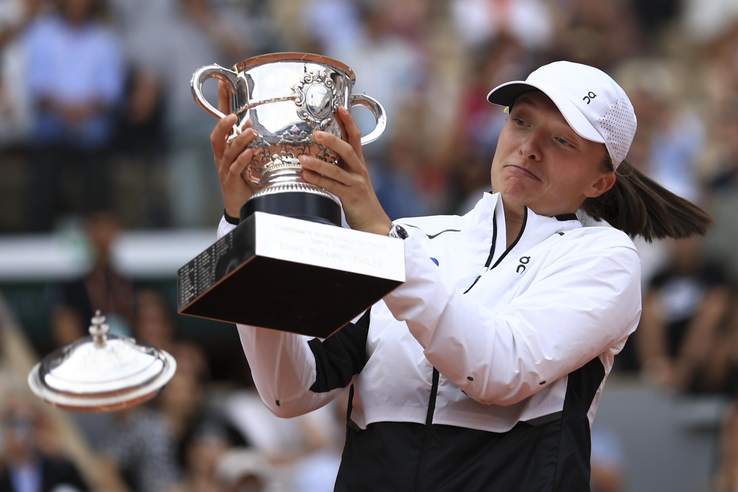 The lid flies off the trophy as Poland's Iga Swiatek celebrates winning the women's final match of the French Open tennis tournament against Karolina Muchova of the Czech Republic in three sets, 6-2, 5-7, 6-4, at the Roland Garros stadium in Paris, Saturday, June 10, 2023.