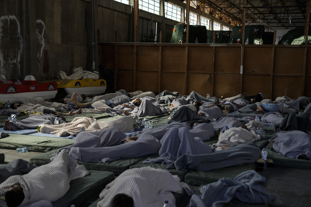 Survivors of a shipwreck sleep at a warehouse at the port in Kalamata town, about 240 kilometers (150 miles) southwest of Athens, Wednesday, June 14, 2023. A fishing boat carrying migrants capsized and sank off the coast of Greece on Wednesday, authorities said, leaving at least 78 people dead and many dozens feared missing in one of the worst disasters of its kind this year.