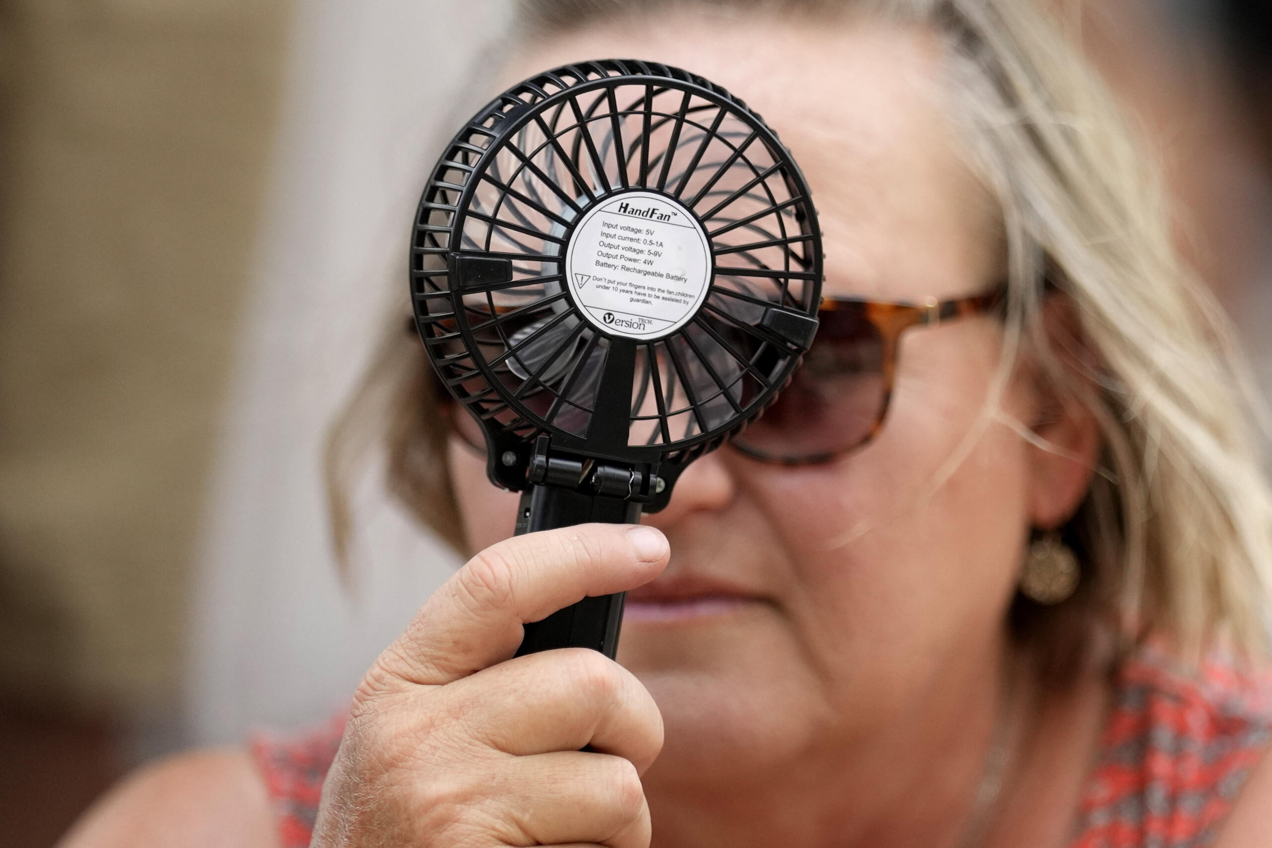 A Houston Astros fan uses a hand fan to keep cool while waiting to enter Minute Maid Park for baseball game against the Cincinnati Reds Saturday, June 17, 2023, in Houston. (AP Photo/David J.