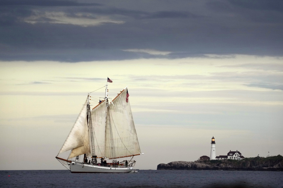 The schooner Timberwind cruises with her guests on a sunset sail off the coast of Cape Elizabeth, Maine, Thursday, June 8, 2023. Portland Head Light stands at the mouth of the harbor in the background. While much of the East Coast is dealing with the smoke from the Canadian wildfires, Maine has been enjoying clean air due to a low pressure system and favorable winds. (AP Photo/Robert F.