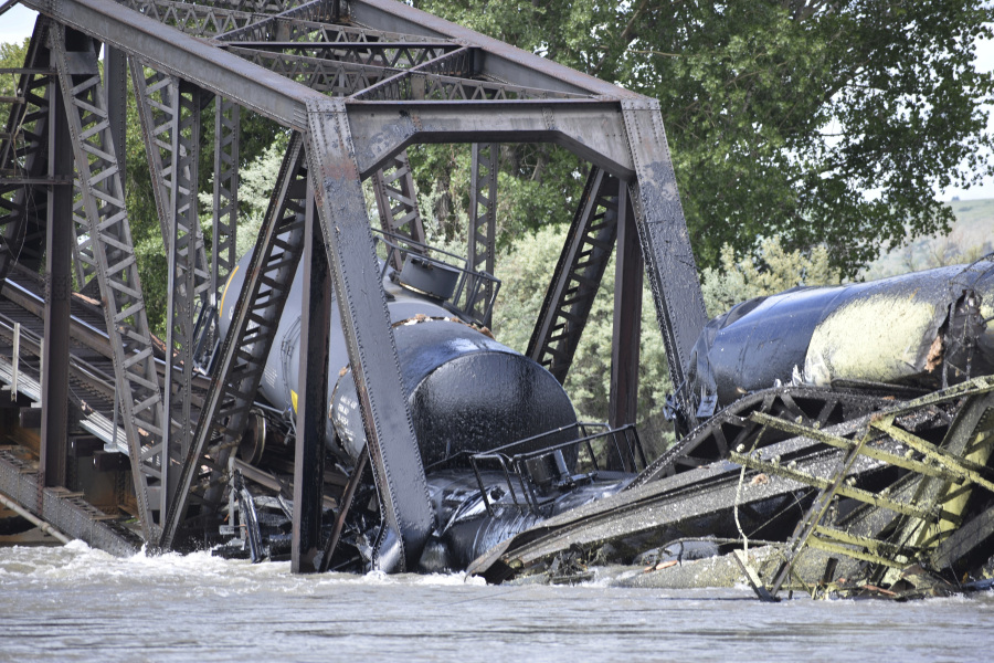Several train cars are immersed in the Yellowstone River after a bridge collapse near Columbus, Mont., Saturday, June 24, 2023. The bridge collapsed overnight, causing a train that was traveling over it to plunge into the water below. Authorities on Sunday were testing the water quality along a stretch of the Yellowstone River where mangled cars carrying hazardous materials remained after crashing into the waterway.