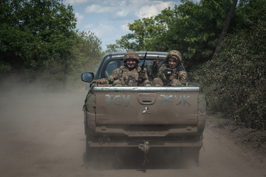 Ukrainian soldiers smile as they ride in a pickup van on the frontline near Bakhmut, the site of fierce battles with the Russian troops in the Donetsk region, Ukraine, Monday, June 5, 2023. Writing on the car reads UAF (Ukrainian Armed Forces).