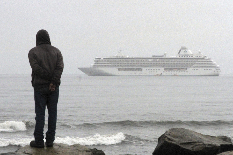 A man stands on the shore of the Bering Sea to watch the luxury cruise ship Crystal Serenity anchored just outside Nome, Alaska, in 2016.