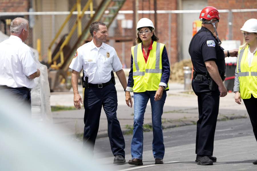 Iowa Gov. Kim Reynolds, center, talks with local officials while touring the site of an apartment building collapse, Monday, June 5, 2023, in Davenport, Iowa. The six-story, 80-unit building partially collapsed May 28.