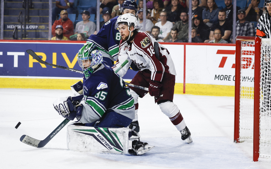 Seattle Thunderbirds goalie Thomas Milic, left, swats away the puck as Peterborough Petes forward Connor Lockhart watches during the second period of a CHL Memorial Cup hockey semifinal Friday, June 2, 2023, in Kamloops, British Columbia.