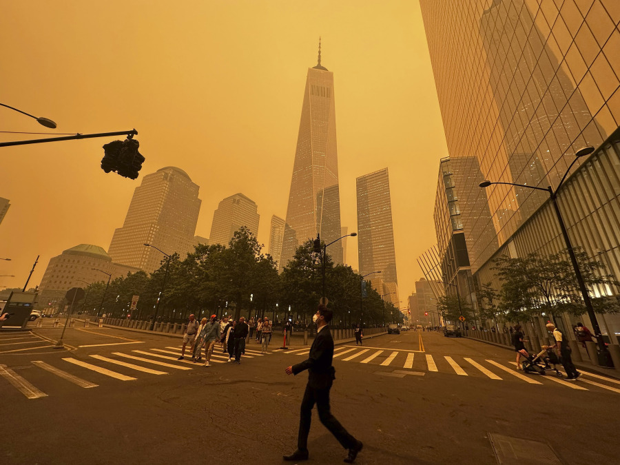 Pedestrians pass the One World Trade Center, center,  amidst a smokey haze from wildfires in Canada, Wednesday, June 7, 2023, in New York. Smoke from Canadian wildfires poured into the U.S. East Coast and Midwest on Wednesday, covering the capitals of both nations in an unhealthy haze, holding up flights at major airports and prompting people to fish out pandemic-era face masks.