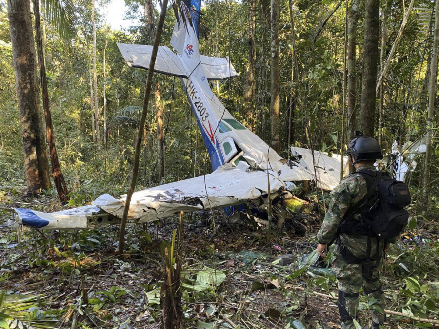 FILE - In this photo released by Colombia's Armed Forces Press Office, a soldier stands in front of the wreckage of a Cessna C206, May 18, 2023, that crashed in the jungle of Solano in the Caqueta state of Colombia. The discovery of footprints on May 30 of a small foot rekindled the hope of finding the children alive after their plane crashed on May 1. Soldiers found the wreckage and the bodies of three adults, including the pilot and the children's mother.