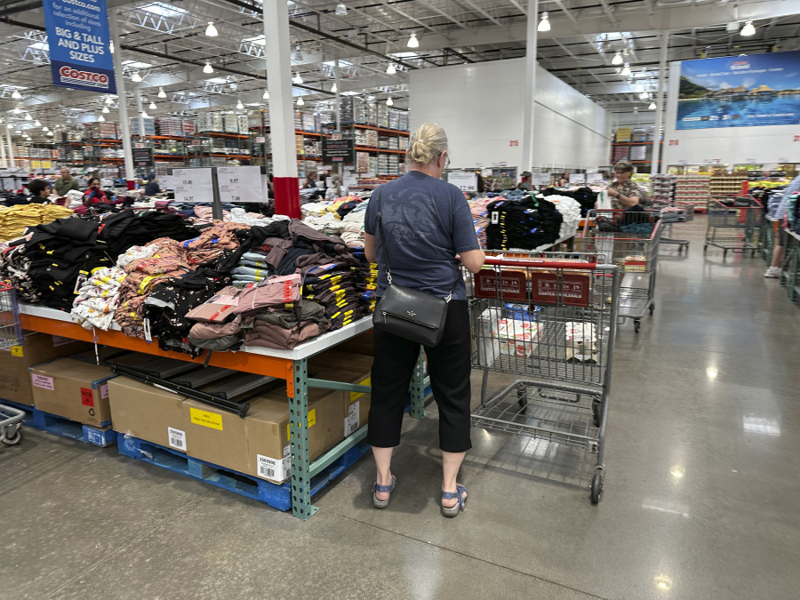 A shopper surveys stacks of clothing on a sales table in a Costco warehouse Thursday, June 22, 2023, in Colorado Springs, Colo. On Friday, the Commerce Department issues its May report on consumer spending. The report contains a measure of inflation that is closely watched by the Federal Reserve.