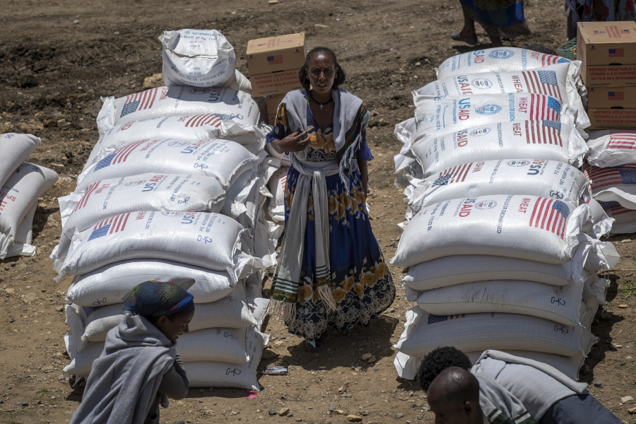 FILE - An Ethiopian woman stands by sacks of wheat to be distributed by the Relief Society of Tigray in the town of Agula, in the Tigray region of northern Ethiopia on May 8, 2021. In 2023 urgently needed grain and oil have disappeared again for millions caught in a standoff between Ethiopia's government, the United States and United Nations over what U.S. officials say may be the biggest theft of food aid on record.