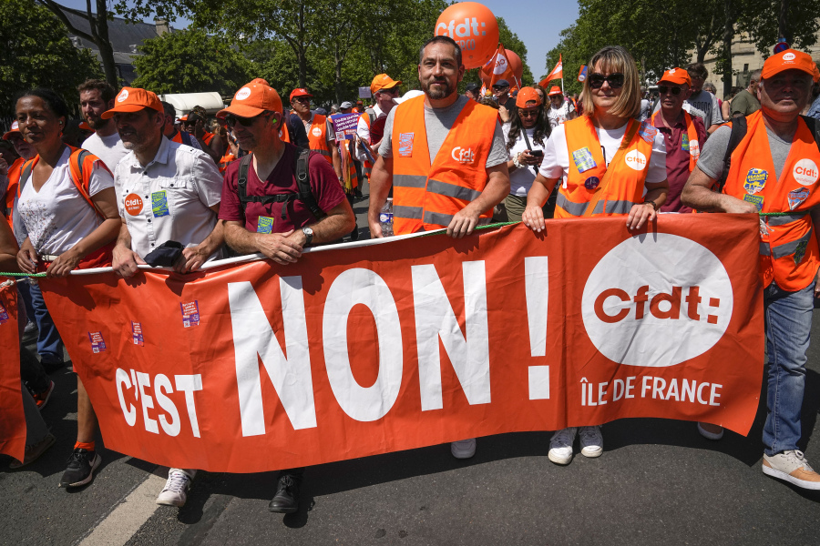 Demonstrators march holding placard reading "No!" in Paris, France, Tuesday, June 6, 2023. French unions are seeking to reignite resistance to President Emmanuel Macron's higher retirement age with what may be a final surge of nationwide protests and scattered strikes Tuesday.