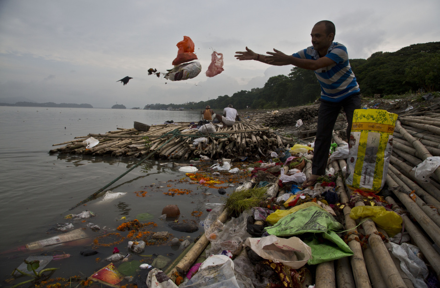 FILE - A Hindu devotee throws flowers and plastic bags into river Brahmaputra in Gauhati, India, Wednesday, Oct. 9, 2019. Negotiators from around the world gather at UNESCO in Paris on Monday, May 29, 2023, for a second round of talks aiming toward a global treaty on fighting plastic pollution in 2024.