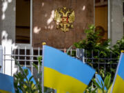 The entrance of the Russian consulate behind small Ukrainian flags placed there for a vigil,  in Frankfurt, Germany, Wednesday, May 31, 2023. Germany authorities says it has told Russia to close four out of five consulates in Germany in a tit-for-tat move after Moscow set a limit for the number of German embassy staff and related bodies that can operate in Russia.