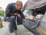 Dr. Kwane Stewart approaches the dog Popcorn protecting his owner's tent June 7 in the Skid Row area of Los Angeles. "The Street Vet," as Stewart is known, has been supporting California's homeless population and their pets for almost a decade.