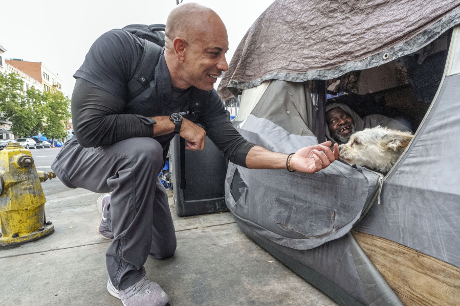 Dr. Kwane Stewart approaches the dog Popcorn protecting his owner's tent June 7 in the Skid Row area of Los Angeles. "The Street Vet," as Stewart is known, has been supporting California's homeless population and their pets for almost a decade.