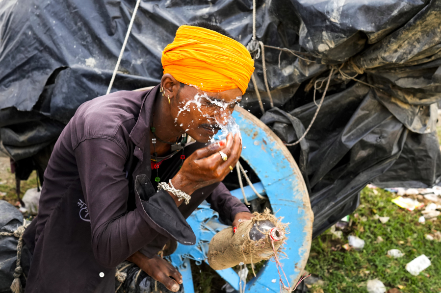 A man splashes water on his face to cool himself on a hot summer afternoon in Lalitpur district in northern Uttar Pradesh state, India, Sunday, June 18, 2023. Swaths of two of India's most populous states are under a grip of sever heat leaving dozens of people dead in several days as authorities issue a warning to residents over 60 and others with ailments to stay indoors during the daytime.
