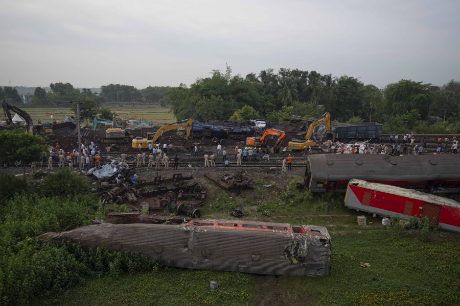 People watch at the site where trains that derailed, in Balasore district, in the eastern Indian state of Orissa, Sunday, June 4, 2023. Indian authorities end rescue work and begin clearing mangled wreckage of two passenger trains that derailed in eastern India, killing over 300 people and injuring hundreds in one of the country's deadliest rail crashes in decades.