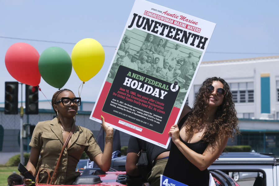 People hold a sign in their car during a car parade to mark Juneteenth on June 19, 2021, in Inglewood, Calif. Communities all over the country will be marking Juneteenth, the day that enslaved Black Americans learned they were free. (Ringo H.W.