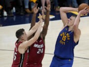 Denver Nuggets center Nikola Jokic, right, shoots over Miami Heat forwards Duncan Robinson, left, and Haywood Highsmith during the first half of Game 1 of basketball's NBA Finals, Thursday, June 1, 2023, in Denver.