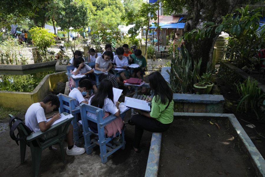 Students attend class under trees because their school was converted into a temporary evacuation center Thursday at Malilipot town, Philippines.