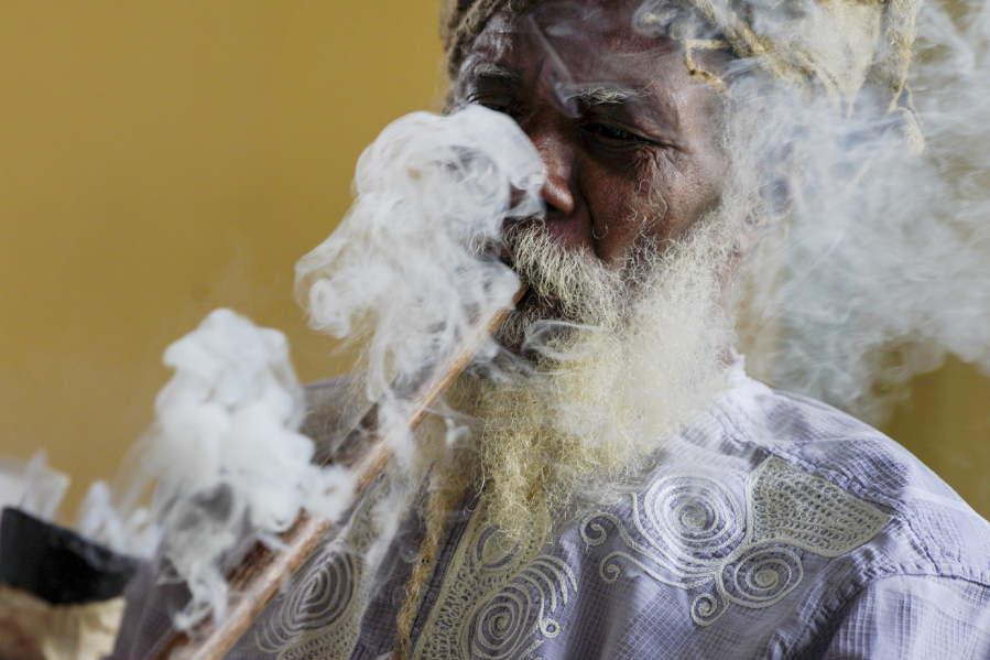 Ras Jah, a member of the Ras Freeman Foundation for the Unification of Rastafari, smokes cannabis from a chalice pipe during service May 14 in the tabernacle in Liberta, Antigua.