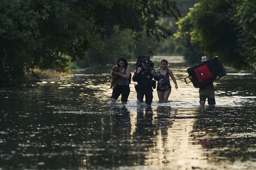 Local residents carry their belongings as they evacuated from a flooded neighborhood in Kherson, Ukraine, Tuesday, June 6, 2023. The wall of a major dam in a part of southern Ukraine has collapsed, triggering floods, endangering Europe's largest nuclear power plant and threatening drinking water supplies.