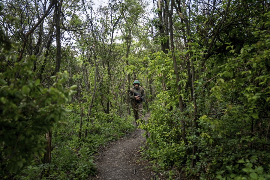 A Ukrainian serviceman of 28th brigade walks to his position at the frontline in Donetsk region, Ukraine, Wednesday, June 21, 2023.