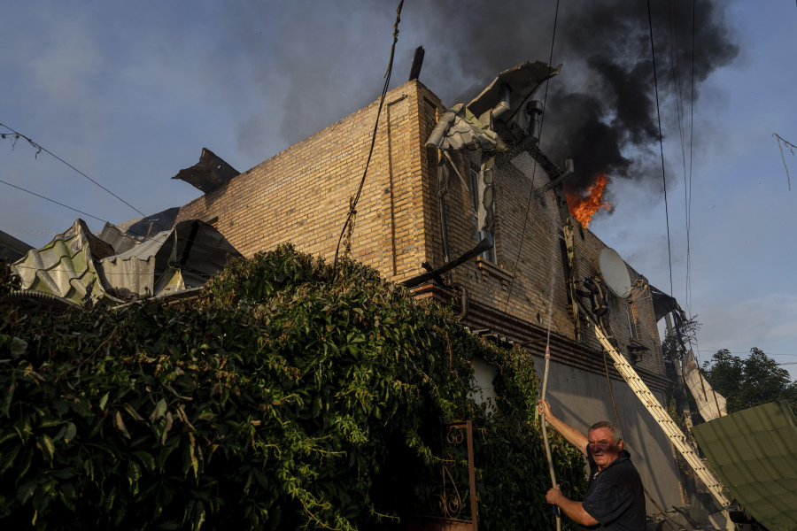 A local man tries to extinguish a fire at a house which was damaged after Russian shelling in Kherson, Ukraine, Friday, June 9, 2023.