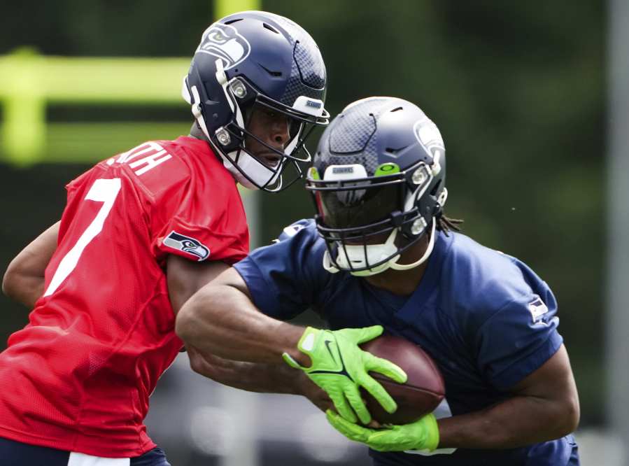 Seattle Seahawks quarterback Geno Smith (7) hands off to running back Kenneth Walker III, Monday, May 22, 2023, at the team's NFL football training facility in Renton, Wash.