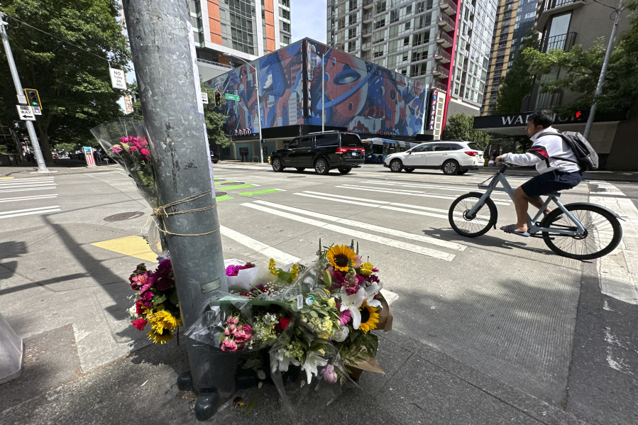 A cyclist rides past a memorial for Eina Kwon in Seattle on Friday, June 16, 2023. A pregnant woman who was killed in what appears to have been a random shooting in downtown Seattle this week has been identified as Eina Kwon, the owner of a sushi restaurant near the city's famed Pike Place Market.