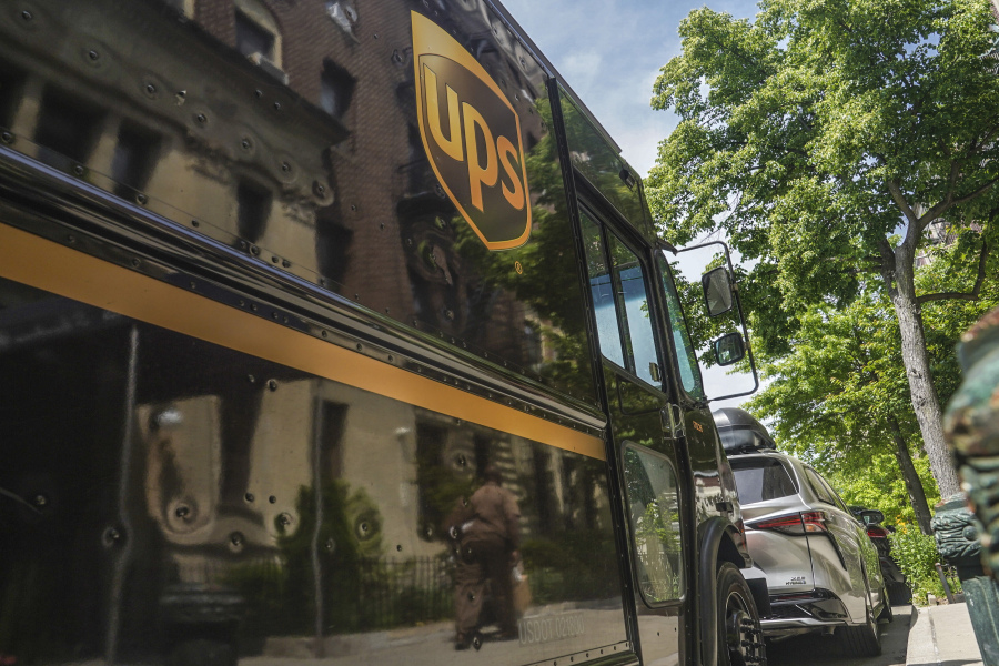 A UPS delivery driver wheeling a load of boxes is reflected on the truck on Friday, May 12, 2023, in New York. More than 340,000 unionized United Parcel Service employees, including drivers and warehouse workers, say they are prepared to strike if the company does not meet their demands before the end of the current contract on July 31.