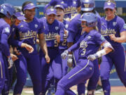 Washington celebrates a home run by Rylee Holtorf (3) at home plate during the second inning of an NCAA softball Women's College World Series game against Utah Friday, June 2, 2023, in Oklahoma City.