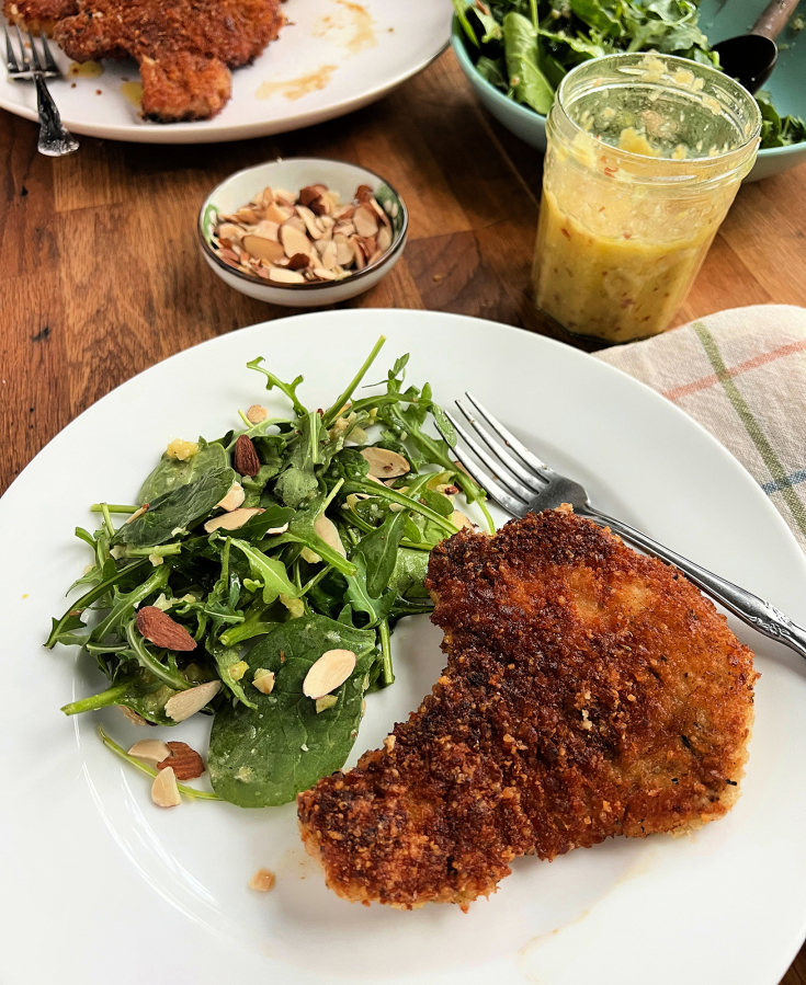 Fried panko-breaded pork chops are paired with an arugula salad dressed in a bright and zesty whole-lemon vinaigrette.