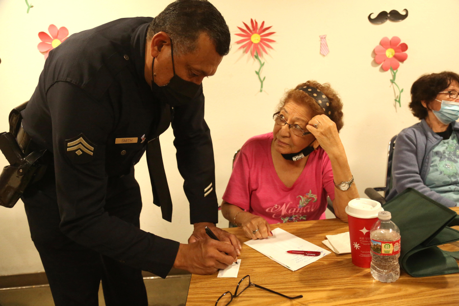 Los Angeles Police Department Det. Albert Smith leaves his card with Marta Barillas, who was robbed recently, after a presentation about financial scams and physical abuse against seniors June 15 at St. Barnabas Senior Services in Los Angeles.
